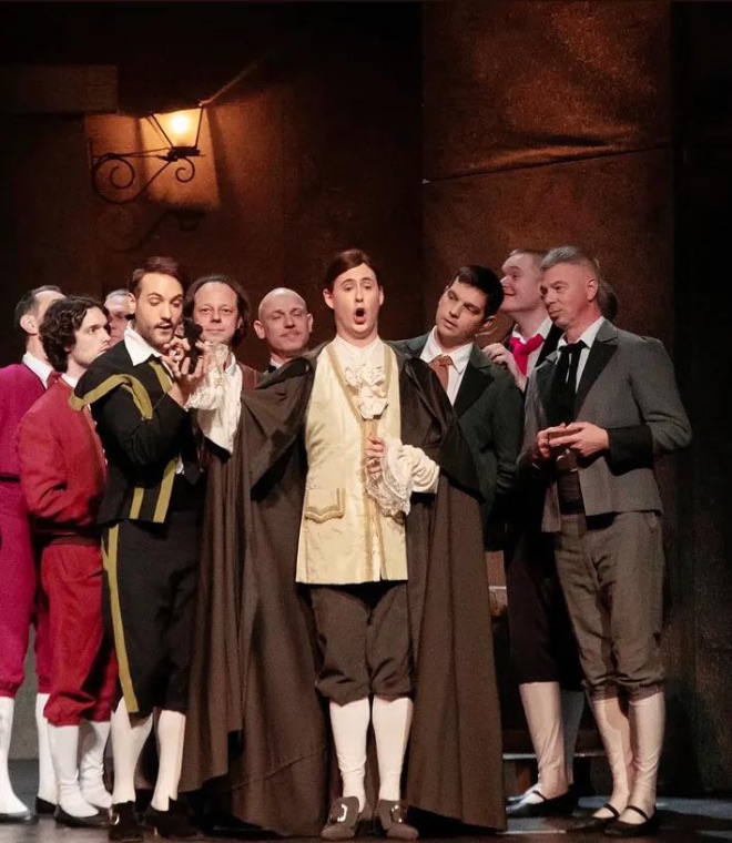 Cloaked male ensemble in a candlelit scene