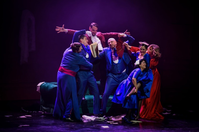 Full ensemble scene under purple stage light