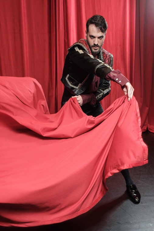 Luka Jozic sweeping a red cloth before a crimson curtain
