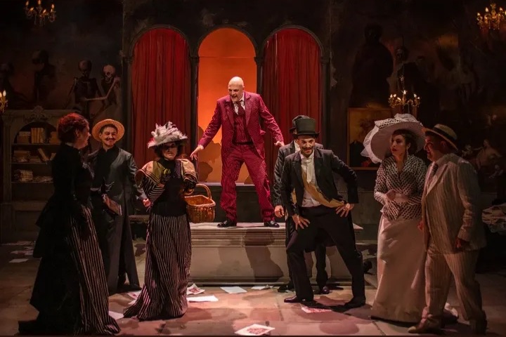 Ensemble scene with a figure in a red striped suit on a plinth